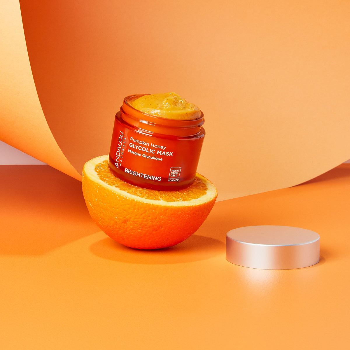 open jar of Brightening Pumpkin Honey Glycolic Mask and half an orange